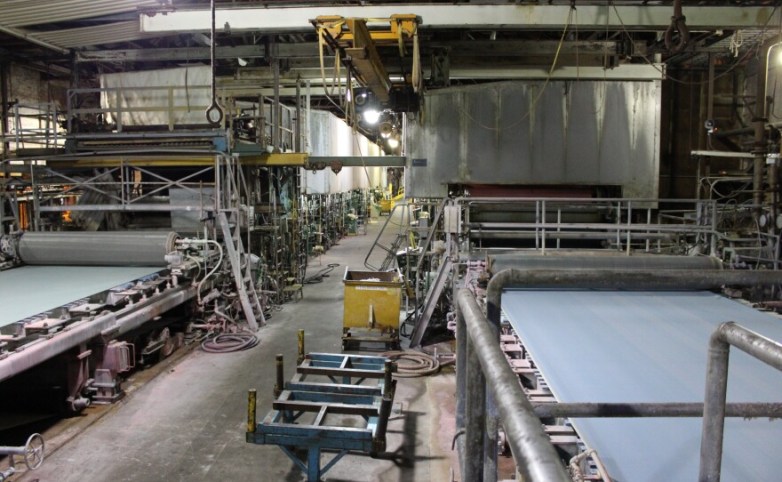 The inside of a factory housing paper machines.