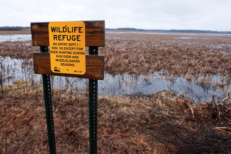 A sign in front of a marshy area says 