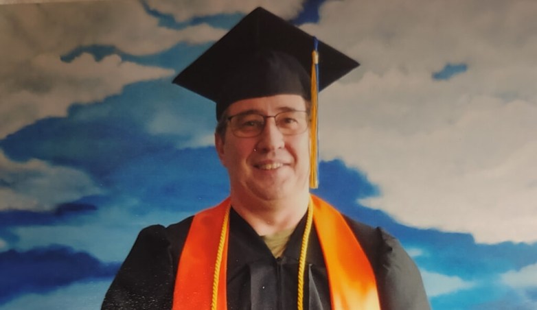 Charles Green poses in a graduation cap and gown.