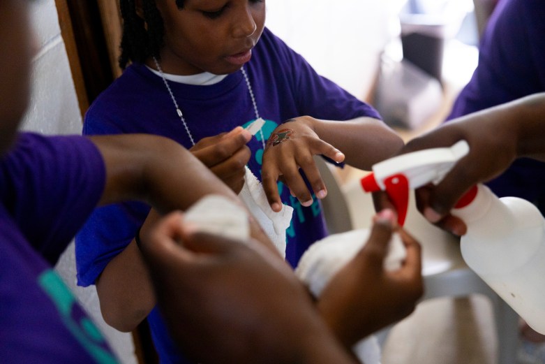A person sprays water from a bottle onto children's hands.