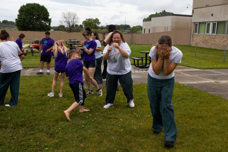 Woman and children have a water balloon fight.