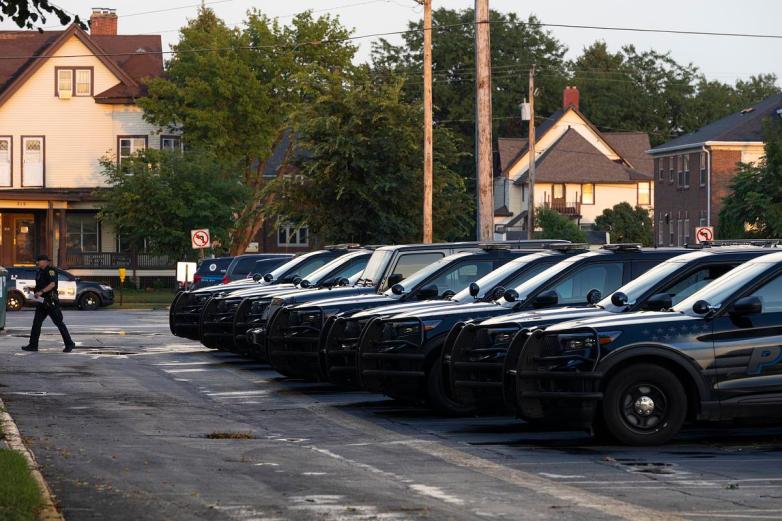 Police officer walks away from row of police cars.
