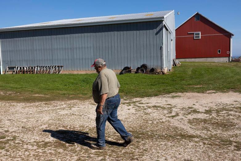 Person walks past farm buildings.