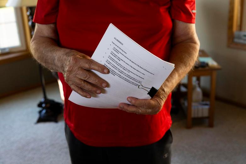 A person wearing a red shirt holds papers clipped together.