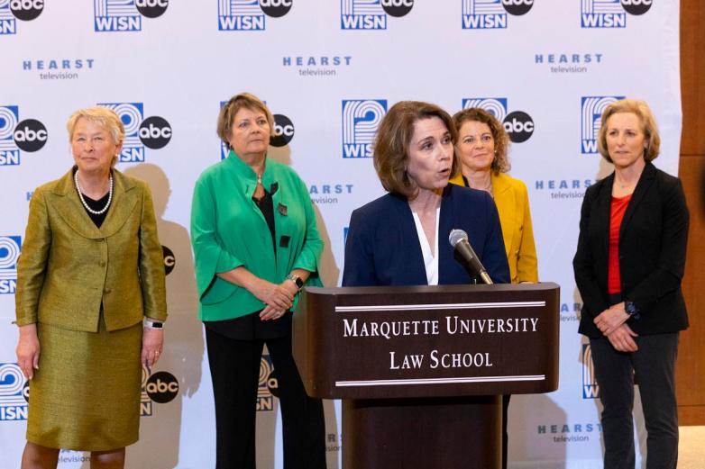 A person speaks at a podium labeled 