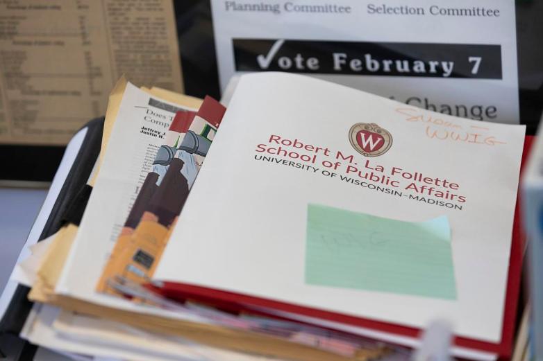 A stack of papers and folders includes a booklet labeled 