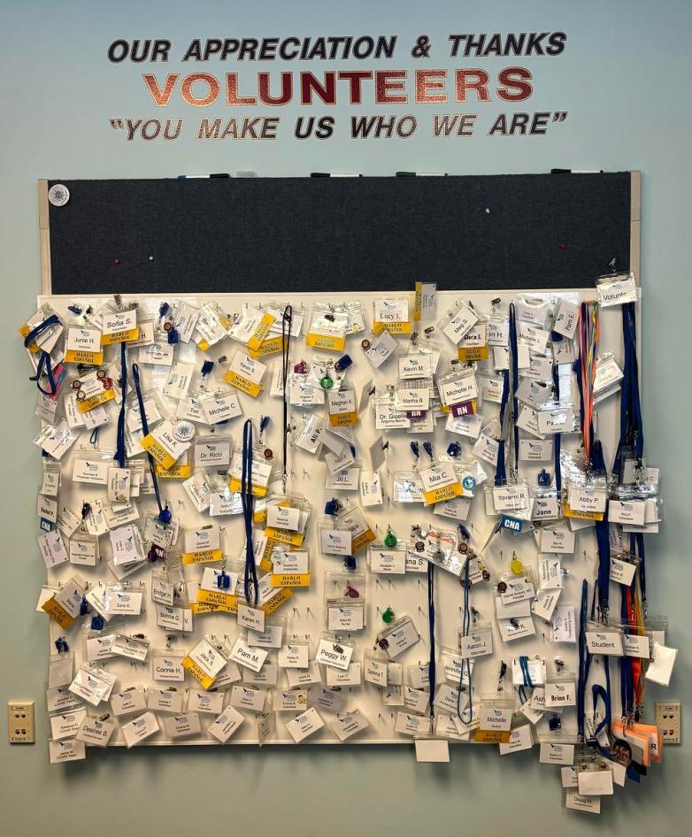 A wall display holds numerous name badges on hooks beneath text reading 