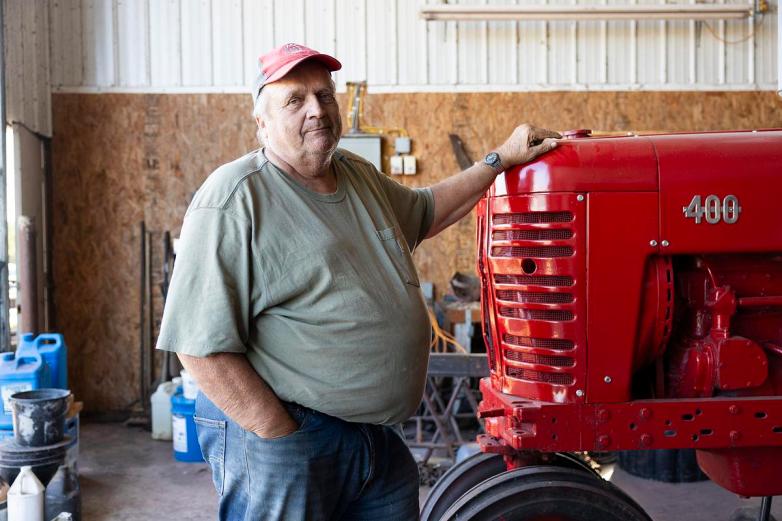 A person rests a hand on a red tractor marked 