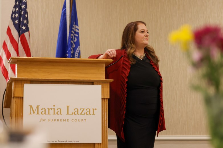 A person stands beside a podium with a sign reading 