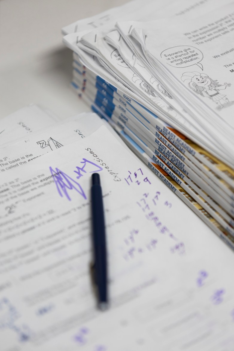 A pen rests on paper next to stacked books labeled